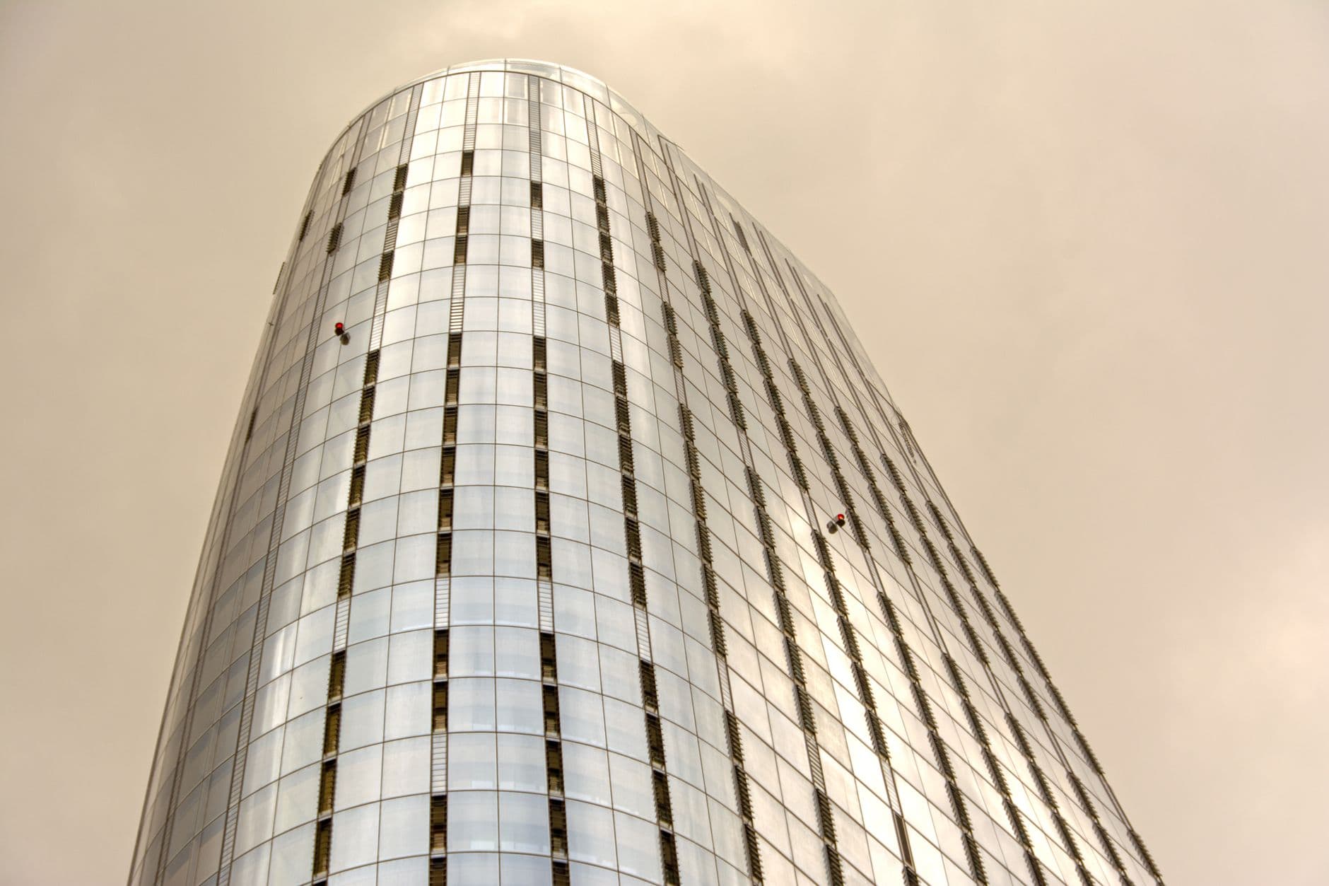 Commercial tower facade cleaning Window cleaners suspended on the glass facade of a modern commercial tower